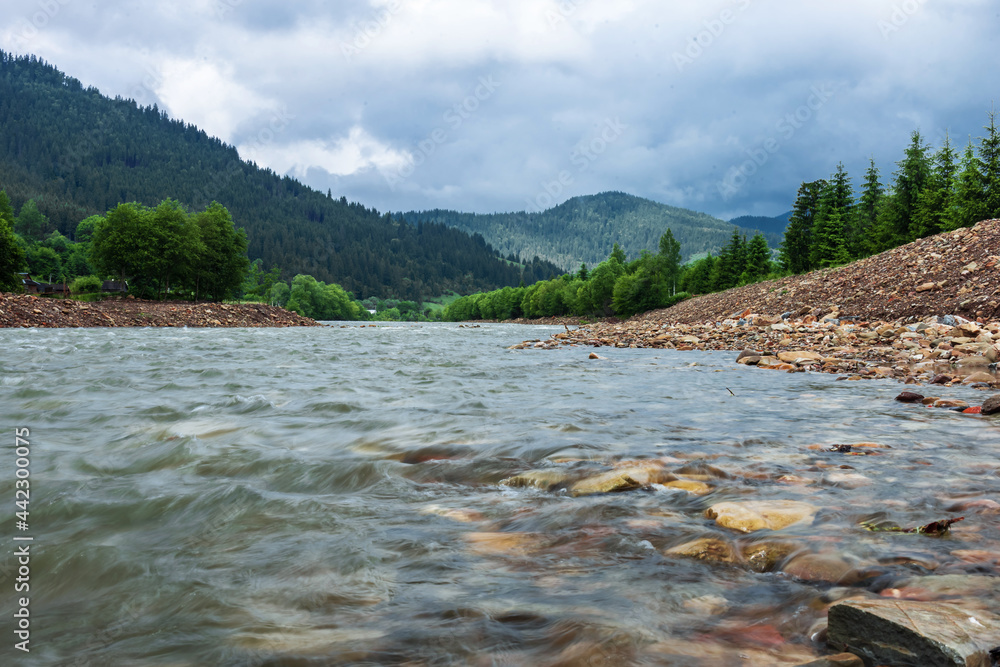 Clear river with rocks leads towards mountains lit. Rafting route Ukrainian Carpathian Mountains Clear river with rocks leads towards mountains lit. Rafting route Ukrainian Carpathian Mountains