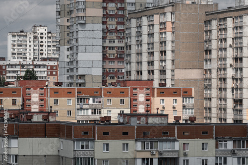 Cityscape of a stuffy post-Soviet city, densely built up with multi-storey residential panel buildings in red and white colors.