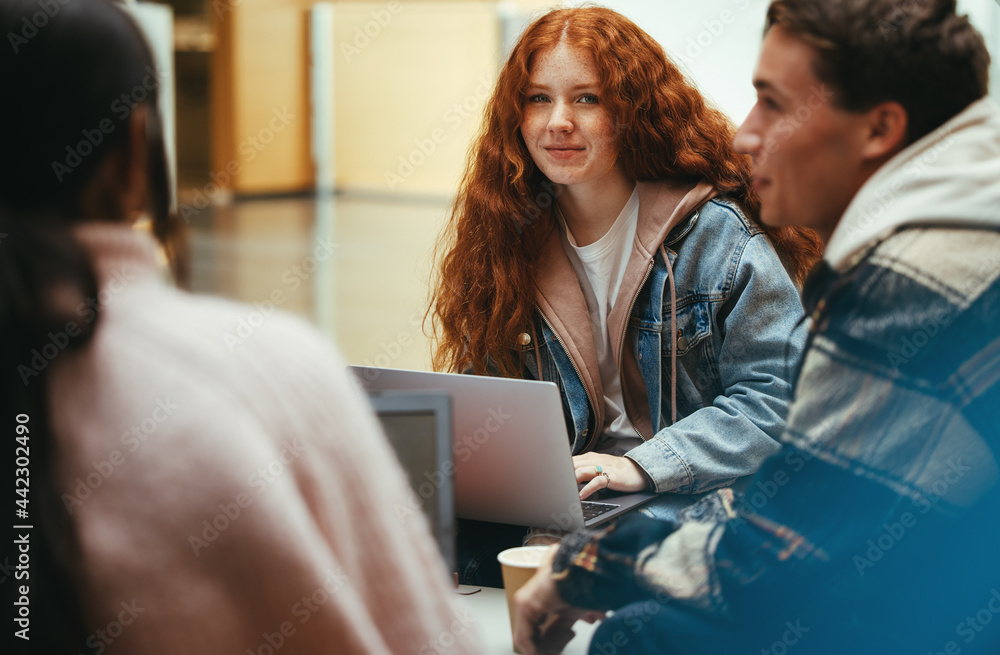 Girl sitting with classmates in college lobby Girl sitting with classmates in college lobby
