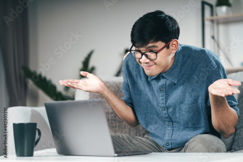 Confused clueless man using laptop computer for Video conference call shrugging shoulders making no idea, whatever gesture I don't know, who cares Concept.