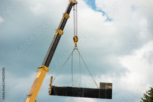The boom of the truck crane lifts part of the formwork against the background of the sky