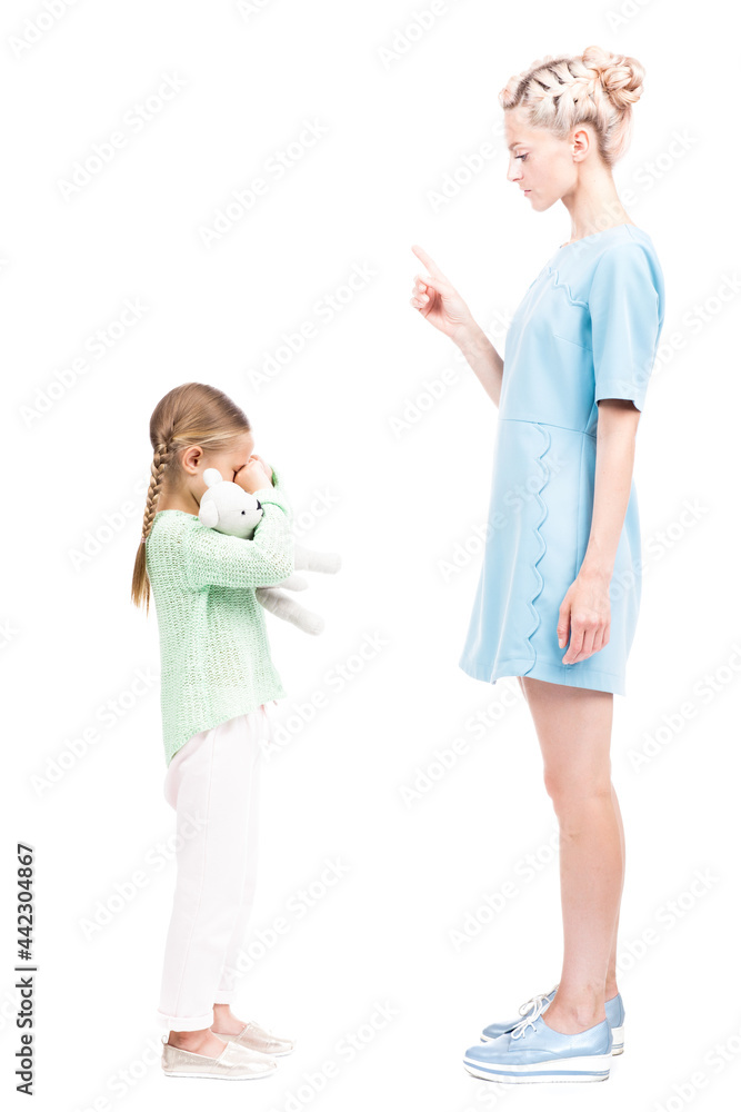 Vertical full length isolated side view shot of young adult woman scolding her daughter for being naughty, white background Vertical full length isolated side view shot of young adult woman scolding her daughter for being naughty, white background