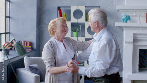 Happy elderly couple dancing at home