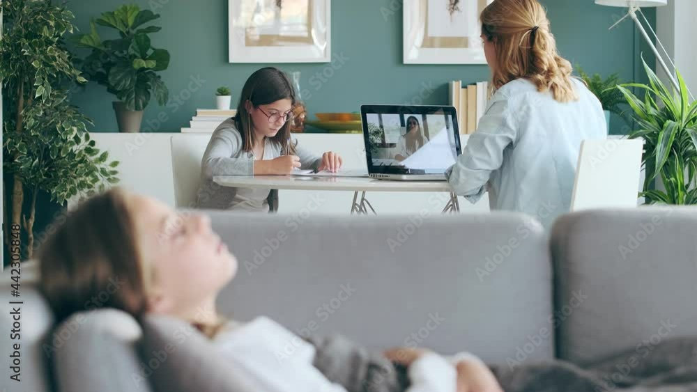 Video of mature mother making videocall with young female doctor while caring for her sick daughter in living room at home. Video of mature mother making videocall with young female doctor while caring for her sick daughter in living room at home.