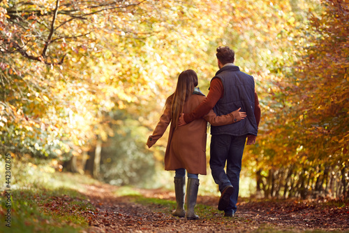 Rear View Of Loving Mature Couple Walking Along Track In Autumn Countryside