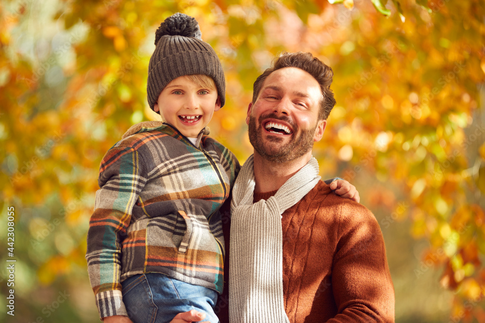Portrait Of Father Holding Son Against Background Of Autumn Leaves On Countryside Walk Portrait Of Father Holding Son Against Background Of Autumn Leaves On Countryside Walk