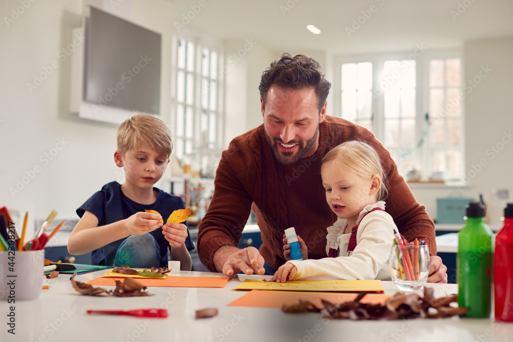 Father With Children At Home Doing Craft And Making Picture From Leaves In Kitchen Father With Children At Home Doing Craft And Making Picture From Leaves In Kitchen