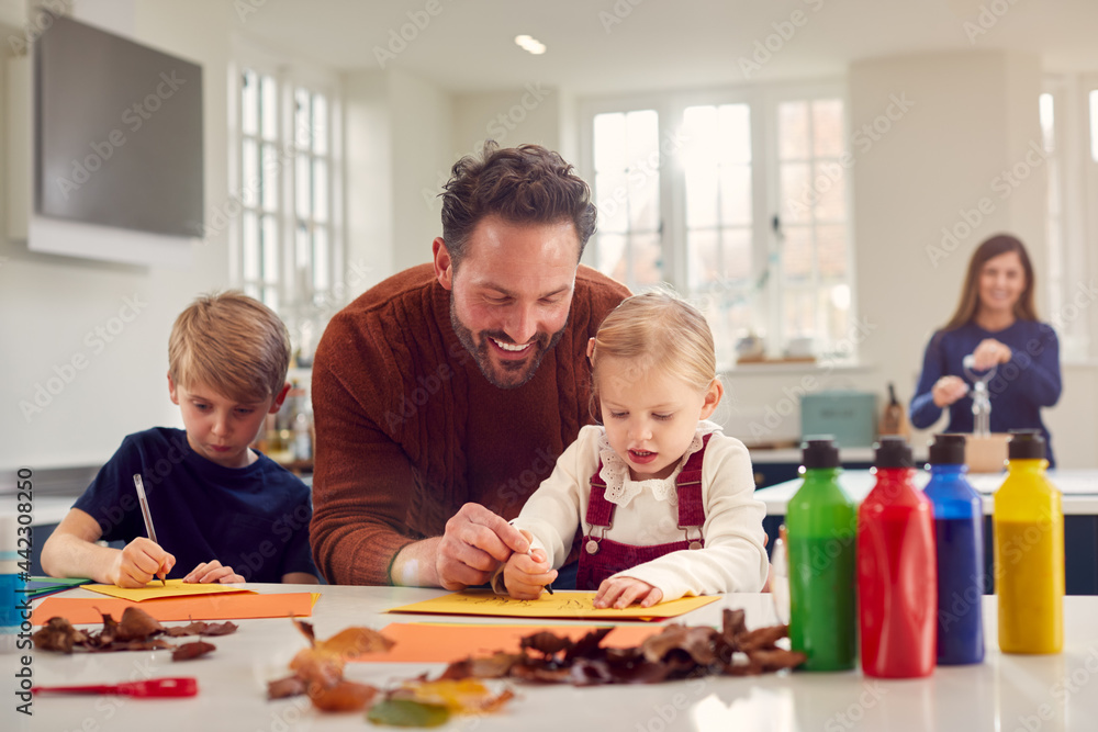 Father With Children At Home Doing Craft And Making Picture From Leaves In Kitchen Father With Children At Home Doing Craft And Making Picture From Leaves In Kitchen