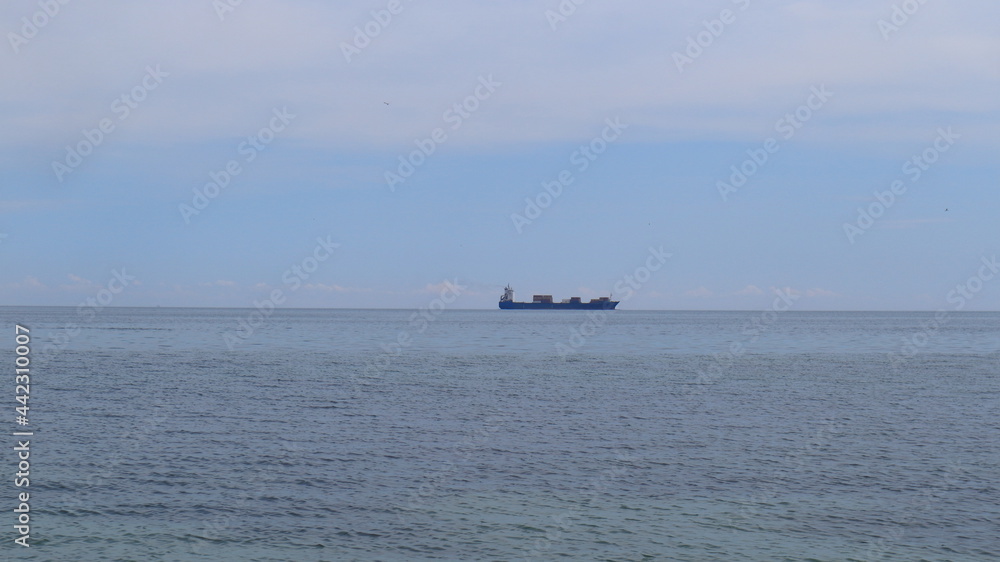 A large merchant ship sails on the horizon of the Black Sea.