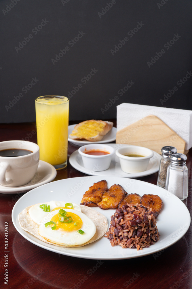 Latin breakfast with all kinds of ingredients like bananas, beans, eggs. coffee and juice to drink
