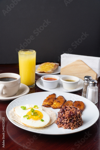 Latin breakfast with all kinds of ingredients like bananas, beans, eggs. coffee and juice to drink 