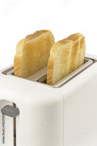 A close up of two slices of golden brown toast in an electrical toaster on a white background