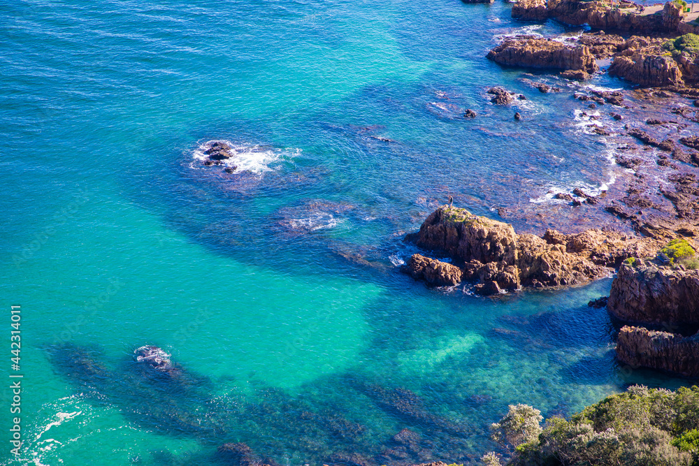 Crystal clear ocean water with rocks protruding from the water at the Knysna Lagoon, South Africa