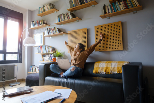 Young casual successful smart woman stuying at home with her laptop. Relaxed female telecommuting. photo