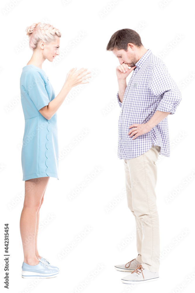 Vertical full length side view studio shot of angry young adult woman quarrelling with her husband, white background Vertical full length side view studio shot of angry young adult woman quarrelling with her husband, white background