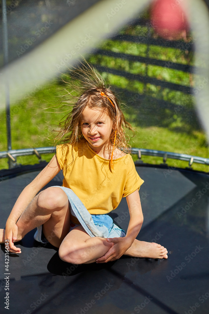 Portrait of young girl with electrified hair on trampoline outdoors, in