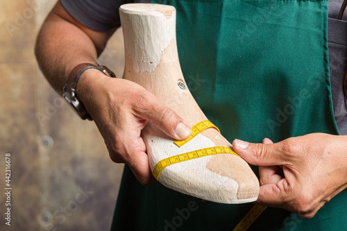 close-up of orthopedic shoemaker measuring a wooden last photo