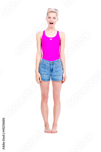 Vertical full length studio portrait of young Caucasian woman wearing summer outfit amused with something, white background