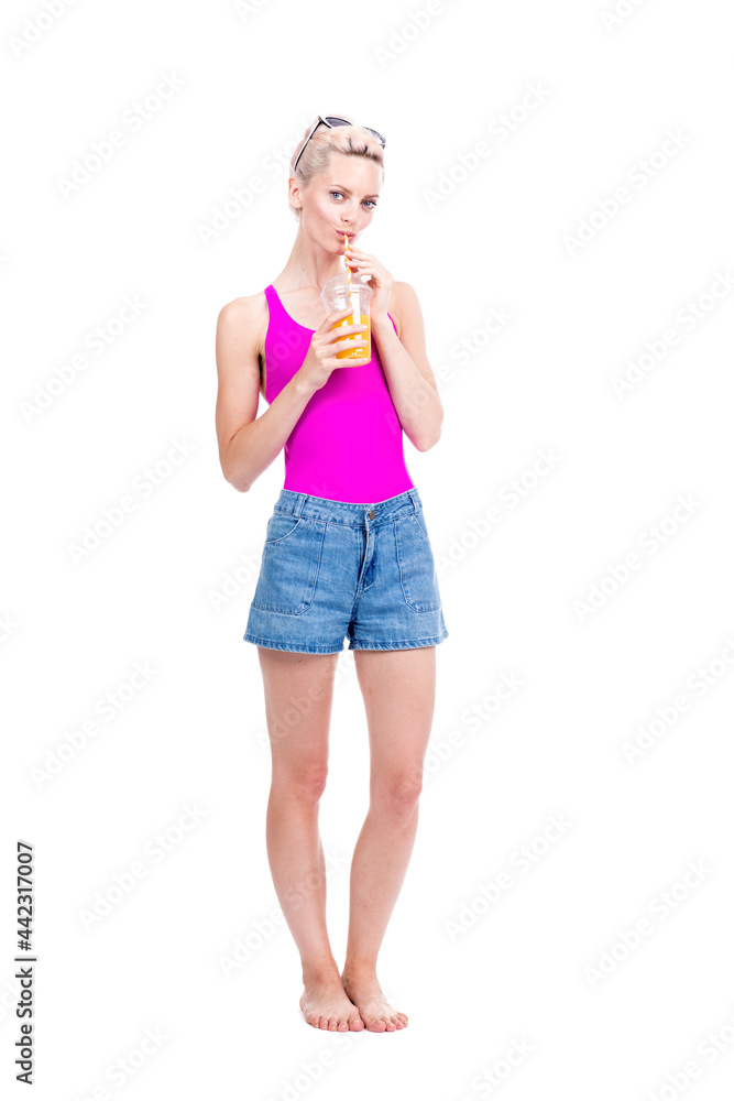 Vertical full length studio portrait of modern young Caucasian woman wearing summer outfit drinking fresh orange juice, white background Vertical full length studio portrait of modern young Caucasian woman wearing summer outfit drinking fresh orange juice, white background