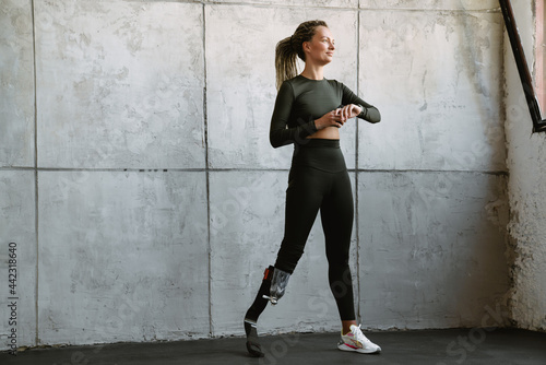 Young sportswoman with prosthesis using smartwatch while working out © Drobot Dean