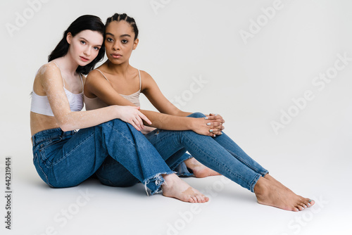 Two young diverse women posing together over © Drobot Dean