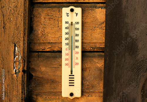 Vintage outdoors thermometer hanging on old wooden wall and showing +28 Celsius temperature.