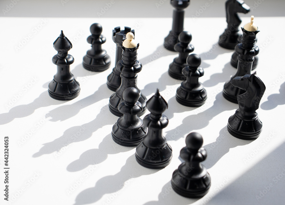 chess, black figures on a light table surface, indoors. Intellectual games for children and adults, logic, thinking, chess on the table, in the shade