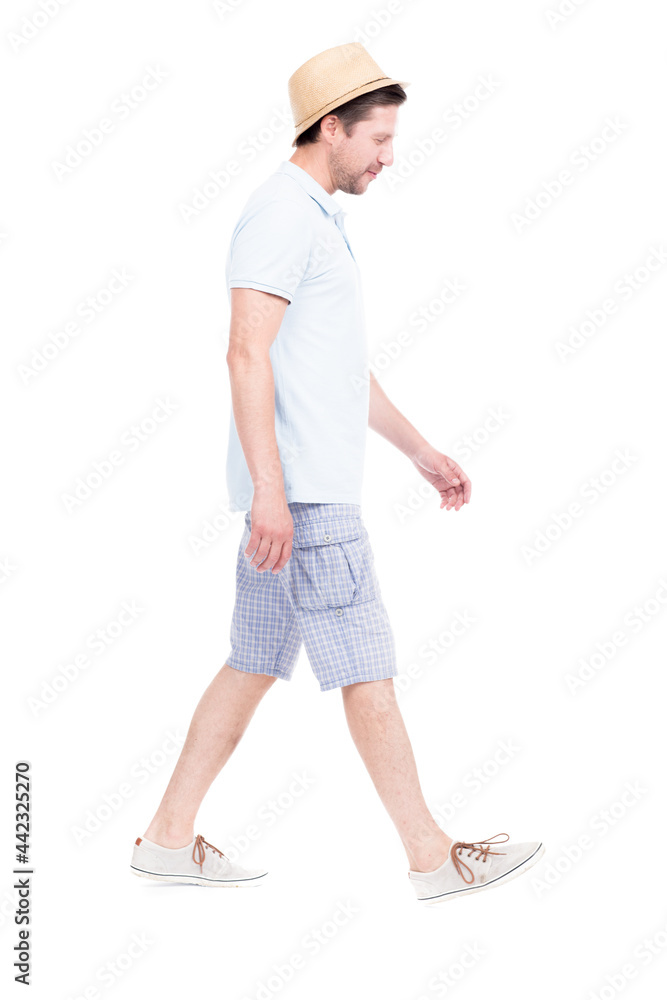 Vertical full length side view portrait of handsome bearded Caucasian man wearing summer outfit with hat walking somewhere, white background Vertical full length side view portrait of handsome bearded Caucasian man wearing summer outfit with hat walking somewhere, white background