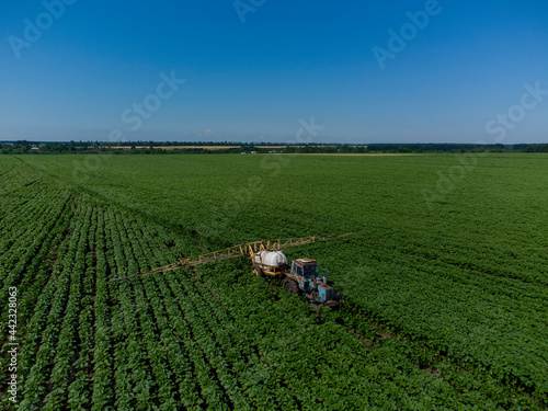 Tractor with a sprayer on a sun field. Application of herbicides.