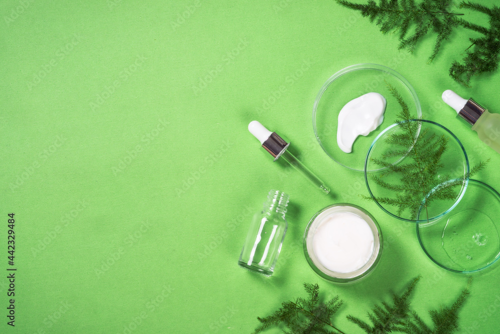 Cosmetic laboratory concept . Glass petri dish with cosmetic products and serum bottles with green plants. Flat lay image with copy space. Cosmetic laboratory concept . Glass petri dish with cosmetic products and serum bottles with green plants. Flat lay image with copy space.