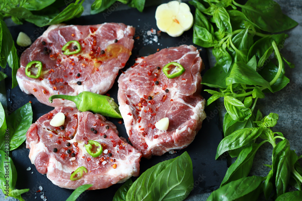 Fresh raw meat steak with spices and fresh basil.