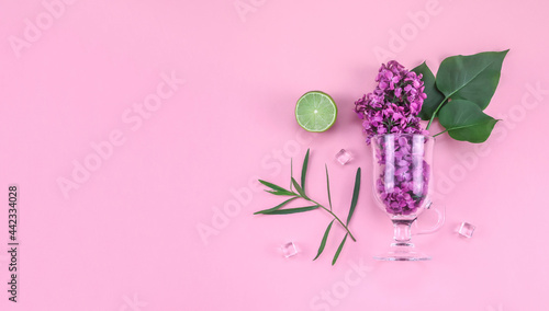 Lilac flowers in a glass on pink.