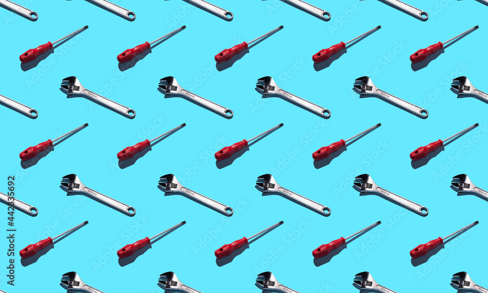 Screwdriver and wrench, pattern on a blue background. Construction tools, repairs. Background for the design. Screwdriver and wrench, pattern on a blue background. Construction tools, repairs. Background for the design.