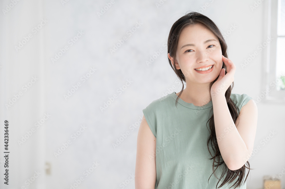 お肌の調子を気にして微笑む若い日本人女性 ズーム　正面　カメラ目線