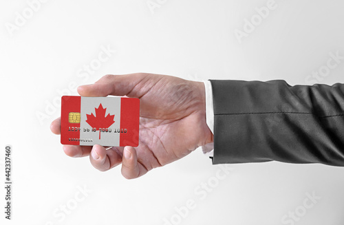 Bank credit plastic card with flag of Canada holding man in elegant suit