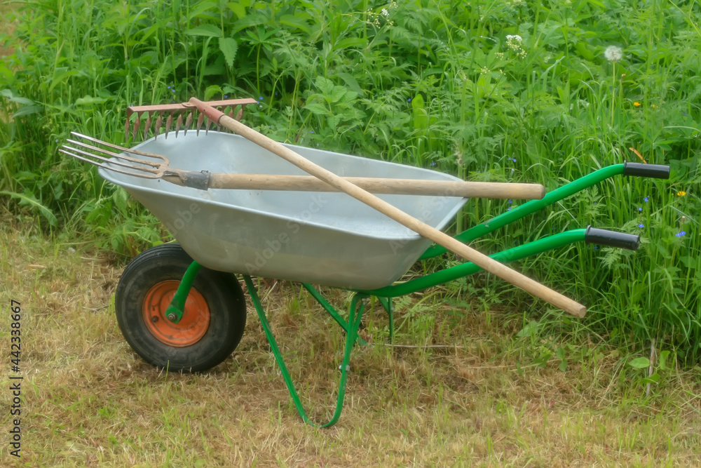Green vegetable garden. Lawn. Mown grass. Garden wheelbarrow. Gardening Tools. Close-up. Green vegetable garden. Lawn. Mown grass. Garden wheelbarrow. Gardening Tools. Close-up.