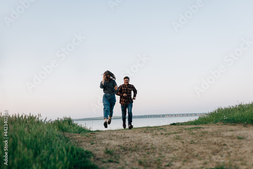 Crazy couple running along the road at sunset. The path leading from the sea and people on it. The guy runs after his happy girlfriend. The concept of a walk and a healthy lifestyle.