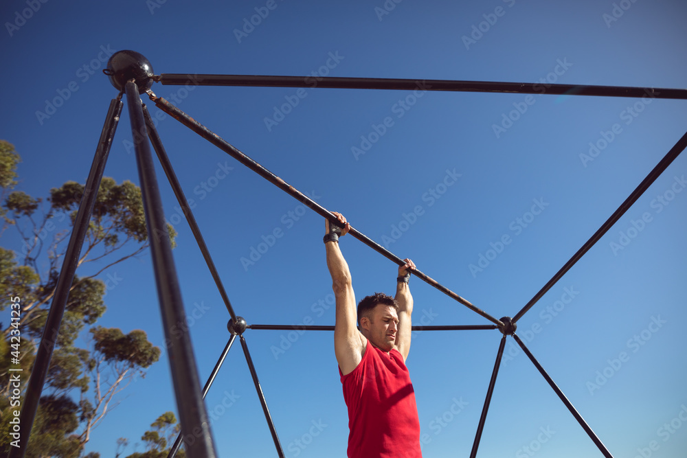 Caucasian muscular man hanging on exercise frame outdoors Caucasian muscular man hanging on exercise frame outdoors