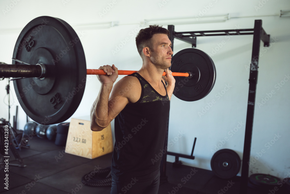 Fit caucasian man exercising at gym, lifting weights on barbell Fit caucasian man exercising at gym, lifting weights on barbell