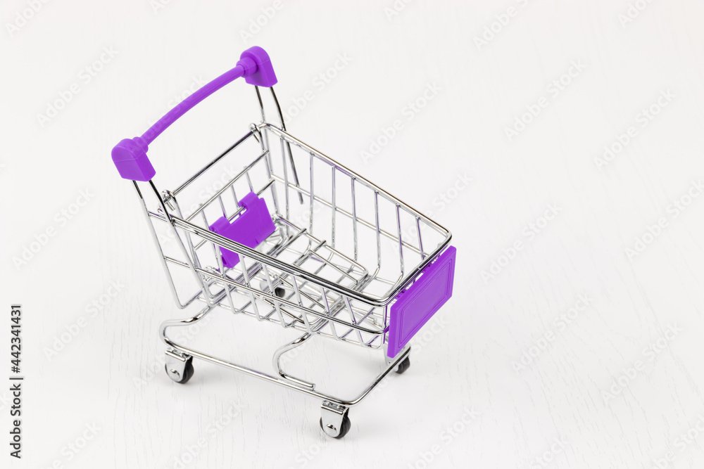 empty metal shiny grocery cart on wheels on white wooden table background empty metal shiny grocery cart on wheels on white wooden table background