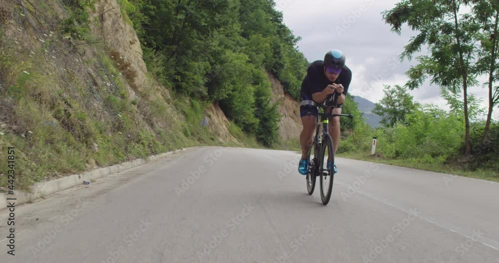 Triathlon sportsman athlete cyclist riding professional racing bicycle. Wearing black sportswear. Triathlon sportsman athlete cyclist riding professional racing bicycle. Wearing black sportswear.