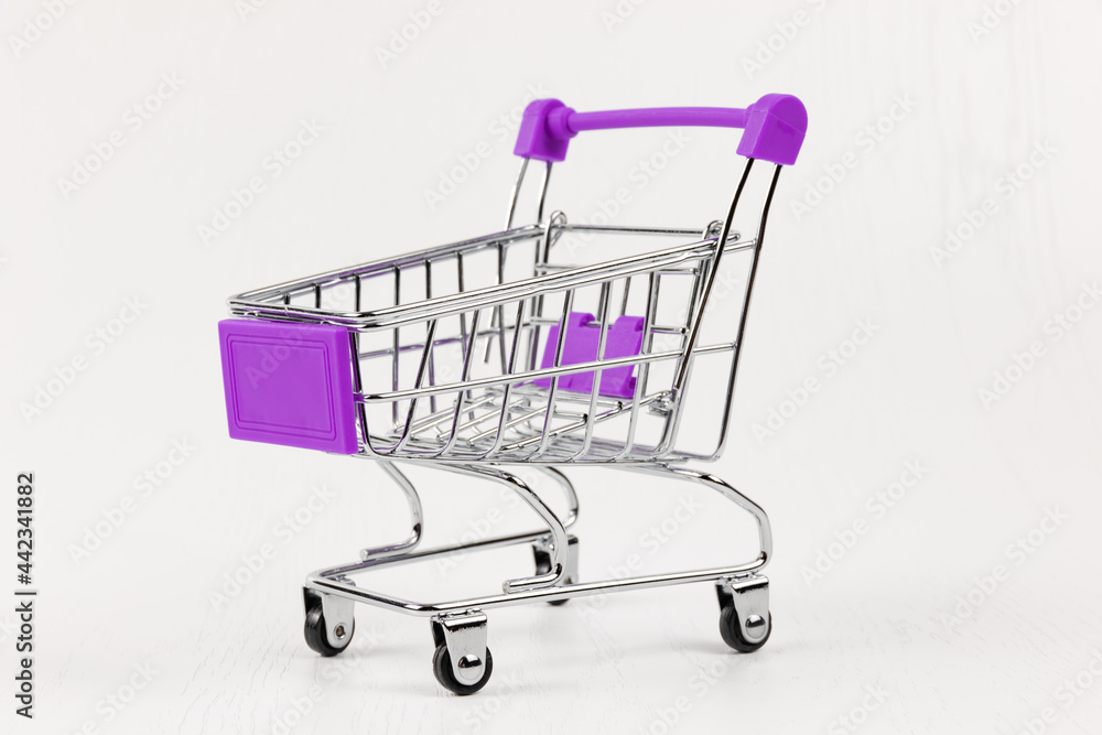 empty metal shiny grocery cart on wheels on white wooden table background empty metal shiny grocery cart on wheels on white wooden table background