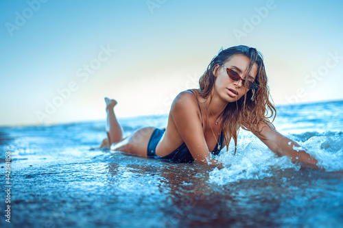 portrait of beautiful sexy caucasian sunbathed woman in leopard print sunglasses with long hair in swimsuit lying on summer beach.