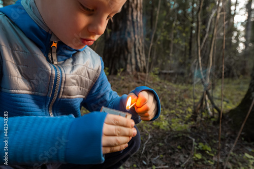 Child lighting match. The fire in the hands of a children. A little boy plays with flame. Danger of woodfire