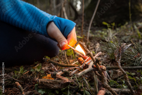Children's hands holding a burning match in a dry forest. Forest fires and sloppy fire handling