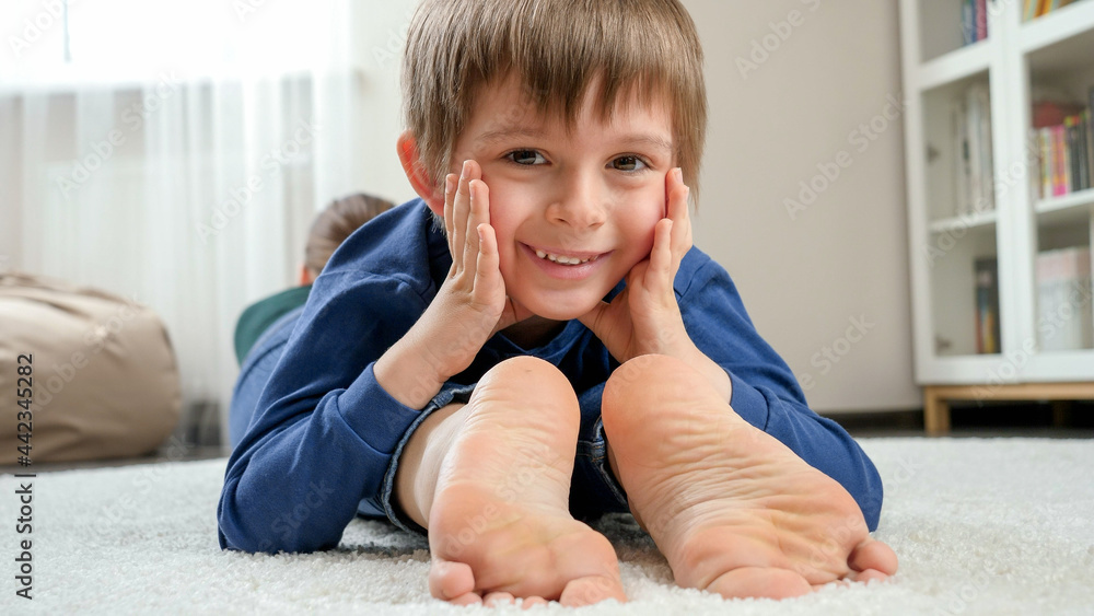 Portrait of happy smiling boy lying on mother's feet and looking in ...