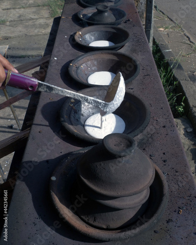 Close up of mother s hand cooking serabi or pancakes in a frying pan made from soil