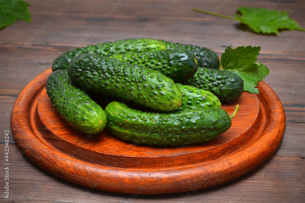 fresh cucumbers with leaves on a cutting board close