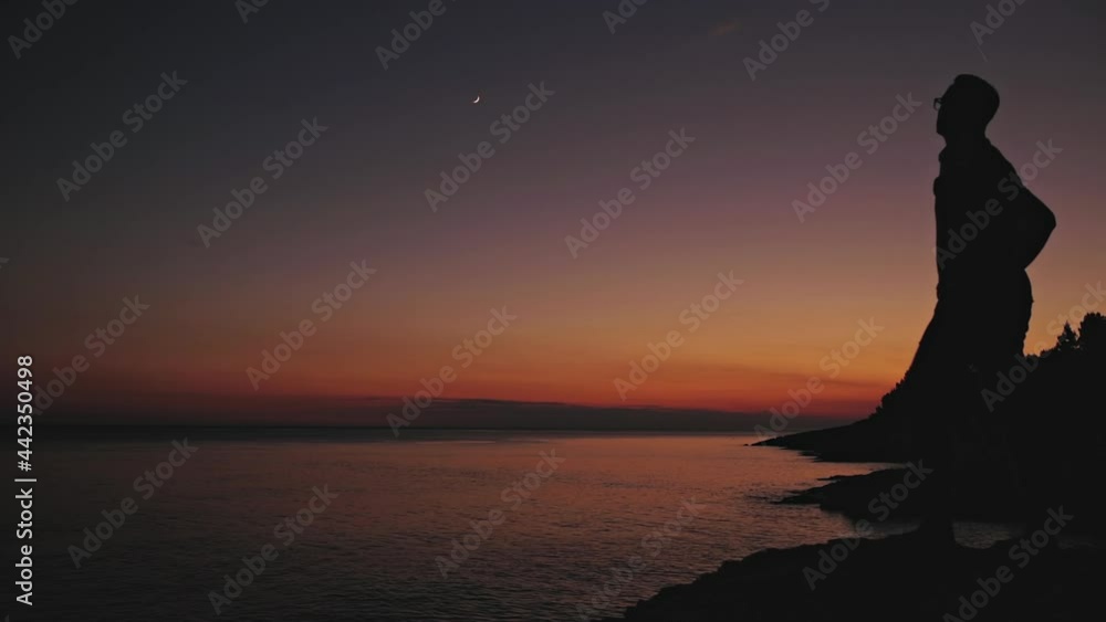 Silhouette of a man looking at the Moon and stars over sea ocean horizon. Silhouette of a man looking at the Moon and stars over sea ocean horizon.