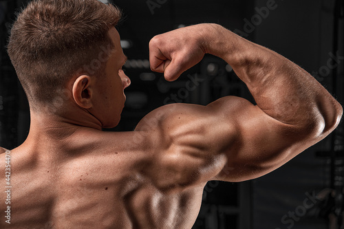 Sport and workout. Athletic bodybuilder man on black background. Dieting and fitness, healthy lifestyle. Coach sportsman showing biceps and triceps. 